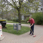 Bürgermeister Dr. Thomas Gans fegt den Bürgersteig und bereitet damit die Fläche für ein Plakat vor.   - Fotos: K.H.Bleß