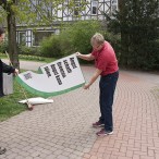 Boris Janssen hilft Thomas Gans, die Folie von einem Plakat abzuziehen.