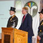 Flankiert von zwei Schornsteinfegern hält Bürgermeister Thomas Gans sein Grußwort.