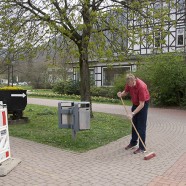 Bürgermeister Dr. Thomas Gans fegt den Bürgersteig und bereitet damit die Fläche für ein Plakat vor.   - Fotos: K.H.Bleß